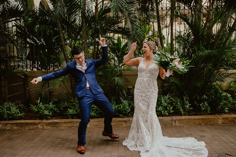 A bride and groom do a goofy dance outside their Cafe Julia wedding in Hawaii 
