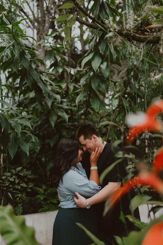 A Seattle couple embrace in front of beautiful plants for engagement photos in the Amazon Headquarters.