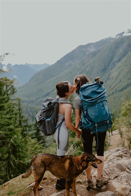 An engaged couple kiss while hiking in Washington for their engagement photos.