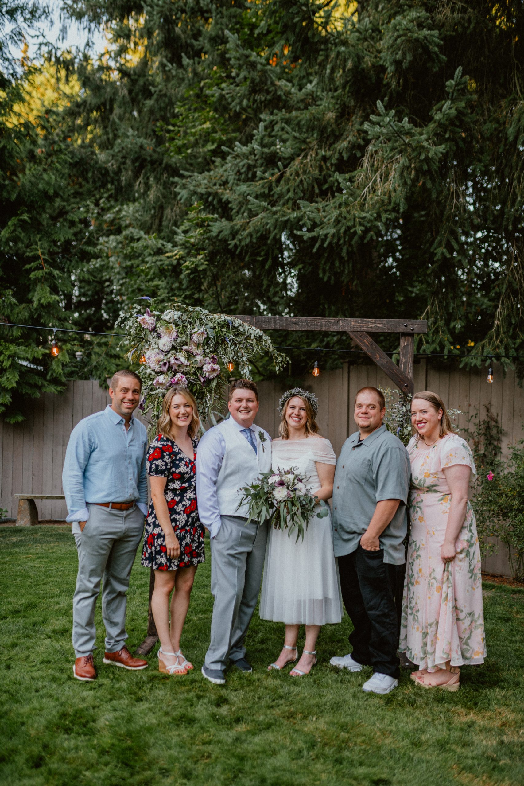 Bride and Groom pose for family photos under DIY flower arch after intimate backyard wedding with family | Seattle Wedding Photographer, Seattle Elopement Photographer | chelseaabril.com