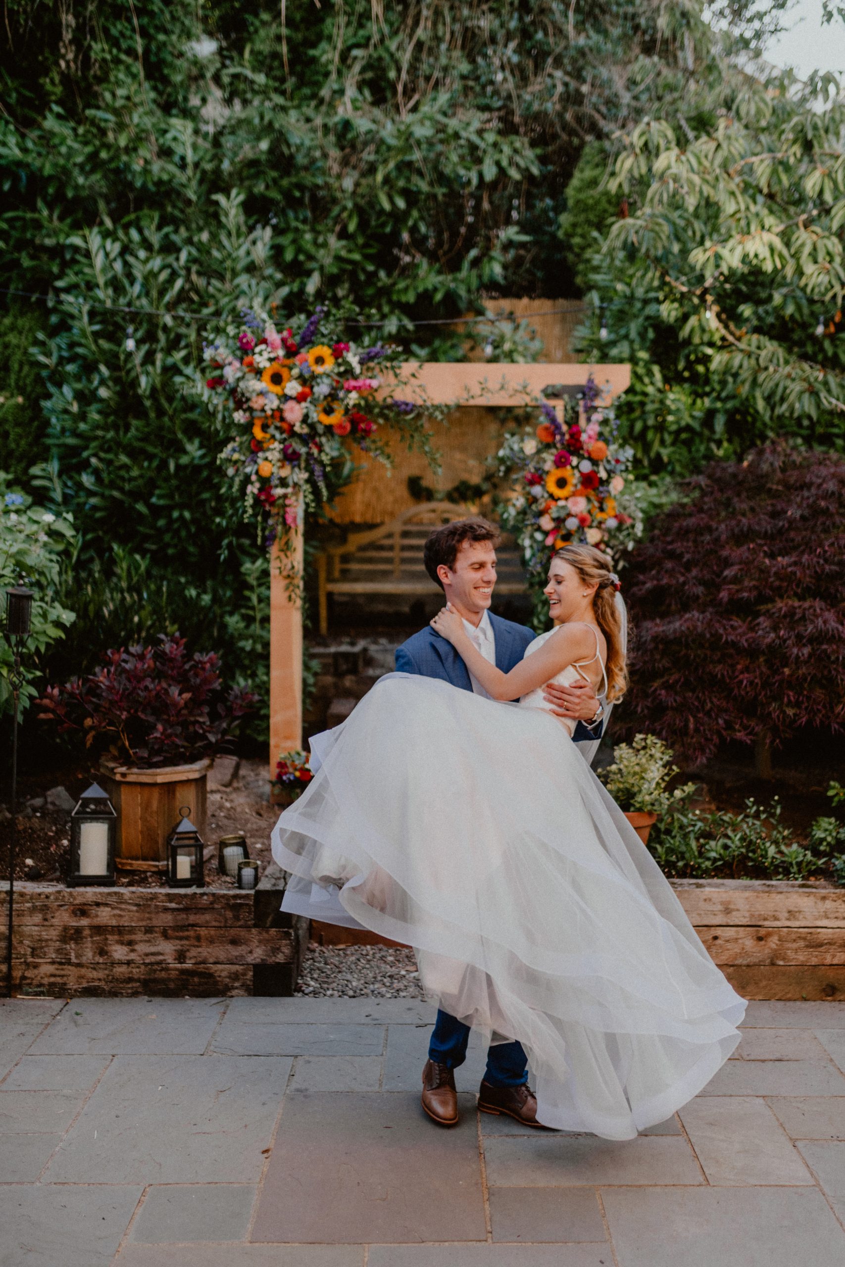 Groom picks up Bride and spins her around in front of outdoor flower arch during wedding ceremony of outdoor Seattle Elopement Wedding | Washington State Elopement Photographer, Seattle Elopement Photographer, Newlywed Elopement Photographer, Quarantine Wedding Elopement Inspiration | chelseaabril.com