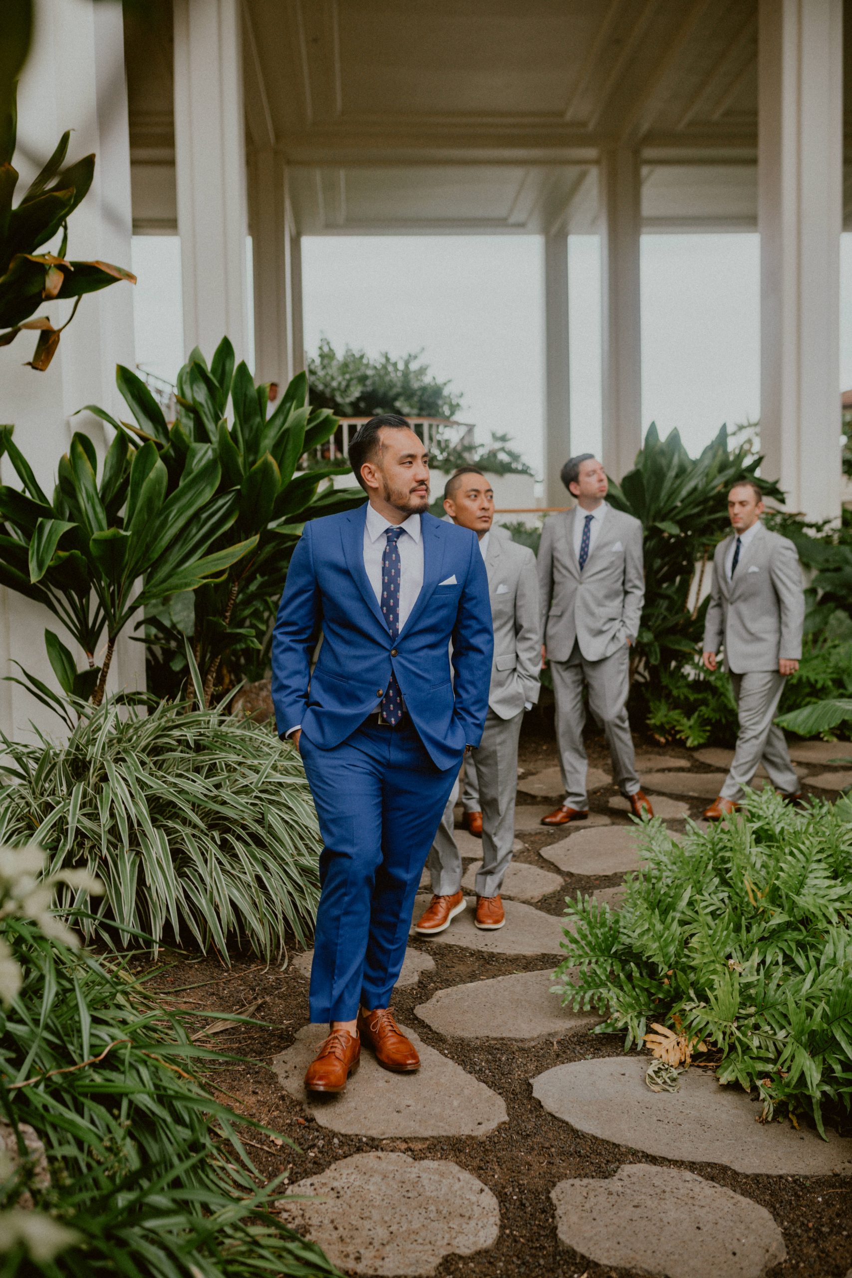Groom in blue suit walks down a stone path in a hotel followed by three groomsmen in grey suits | Groom style tips, Groom wedding day inspiration, Groom Tips Wedding, Groom tips for men, Groom tips | chelseaabril.com