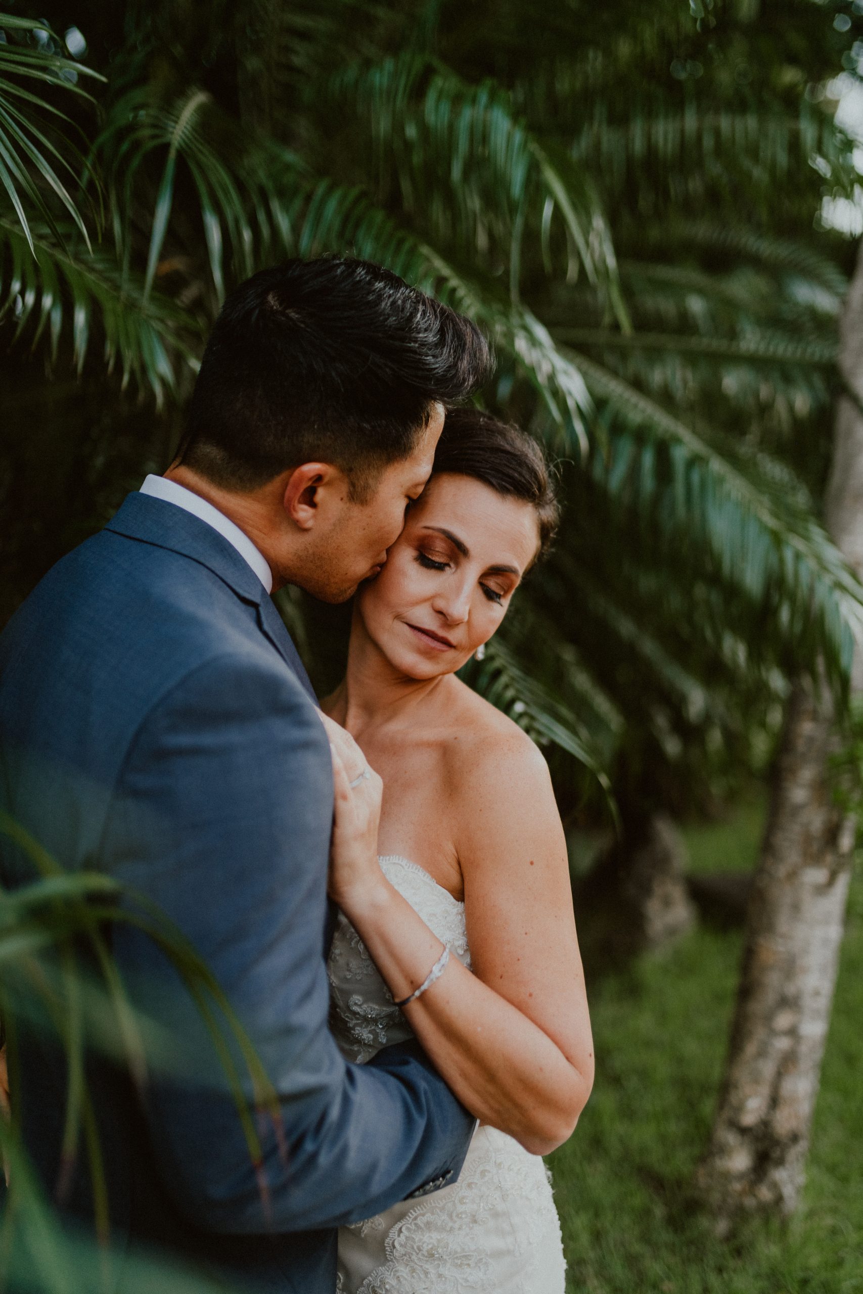 Bride and Groom snuggle in the palm trees on Oahu