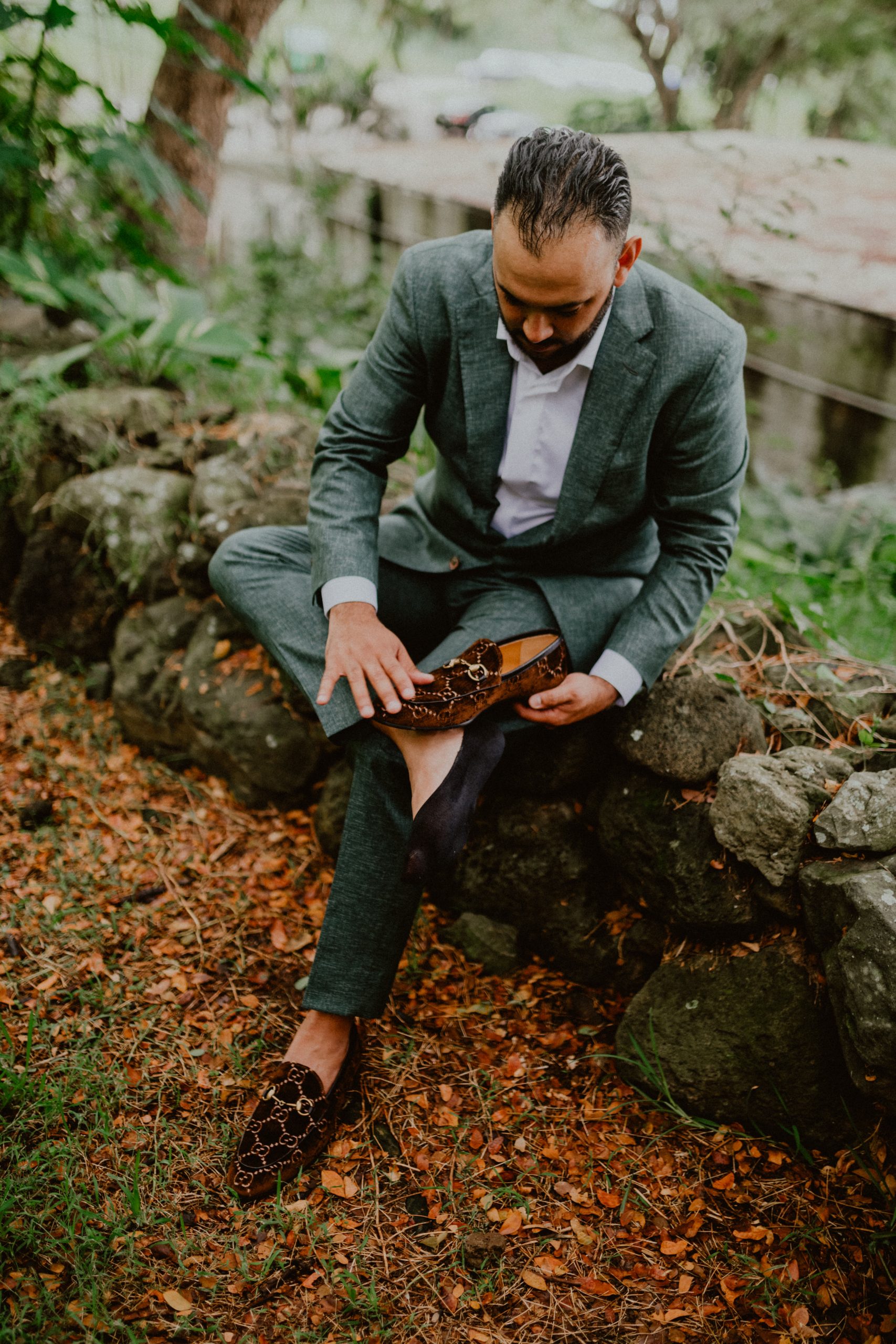 Groom adjusts his Gucci loafers pre-wedding ceremony while wearing his grey linen suit and white button down shirt | Oahu Wedding Photographer, Oahu Elopement Photographer, Destination Wedding Photographer, Destination Elopement Photographer, Newlywed moments ideas, Newlywed Photography inspiration, Hawaii Elopement ideas | chelseaabril.com