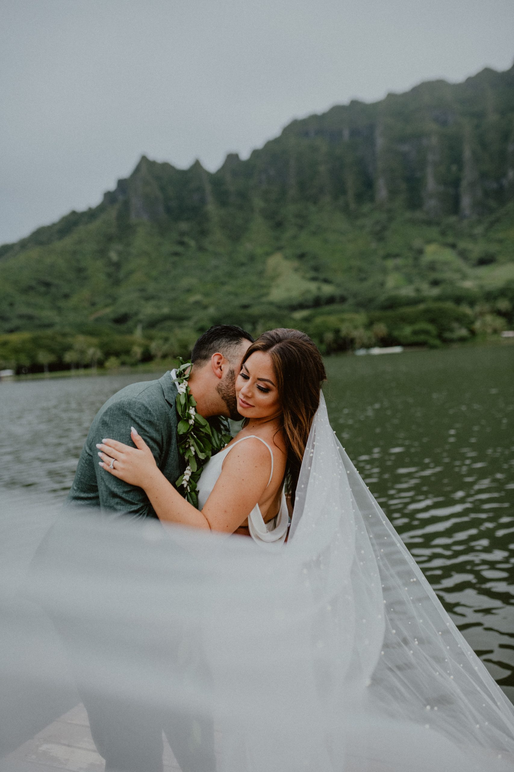 Bride and groom pose together after their wedding day on Kualoa Ranch while standing in front of the water on the beach in Oahu | Oahu Wedding Photographer, Oahu Elopement Photographer, Destination Wedding Photographer, Destination Elopement Photographer, Newlywed moments ideas, Newlywed Photography inspiration, Hawaii Elopement ideas | chelseaabril.com