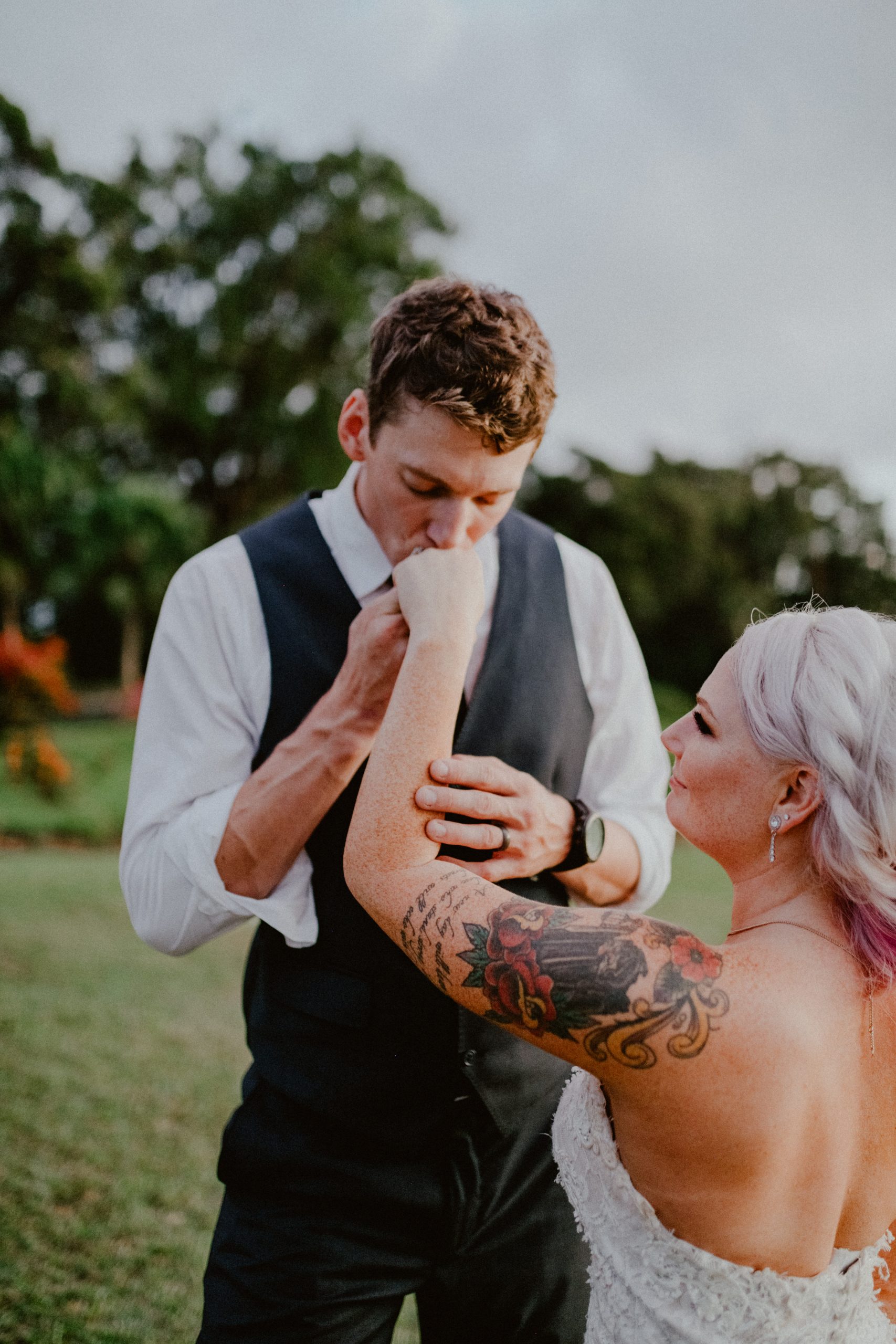 Groom kisses tattooed bride's hand after sliding on wedding band during ceremony at Sunset Ranch Oahu | Oahu Wedding Photographer, Oahu Elopement Photographer, Destination Wedding Photographer, Destination Elopement Photographer, Newlywed moments ideas, Newlywed Photography inspiration, Hawaii Elopement ideas | chelseaabril.com