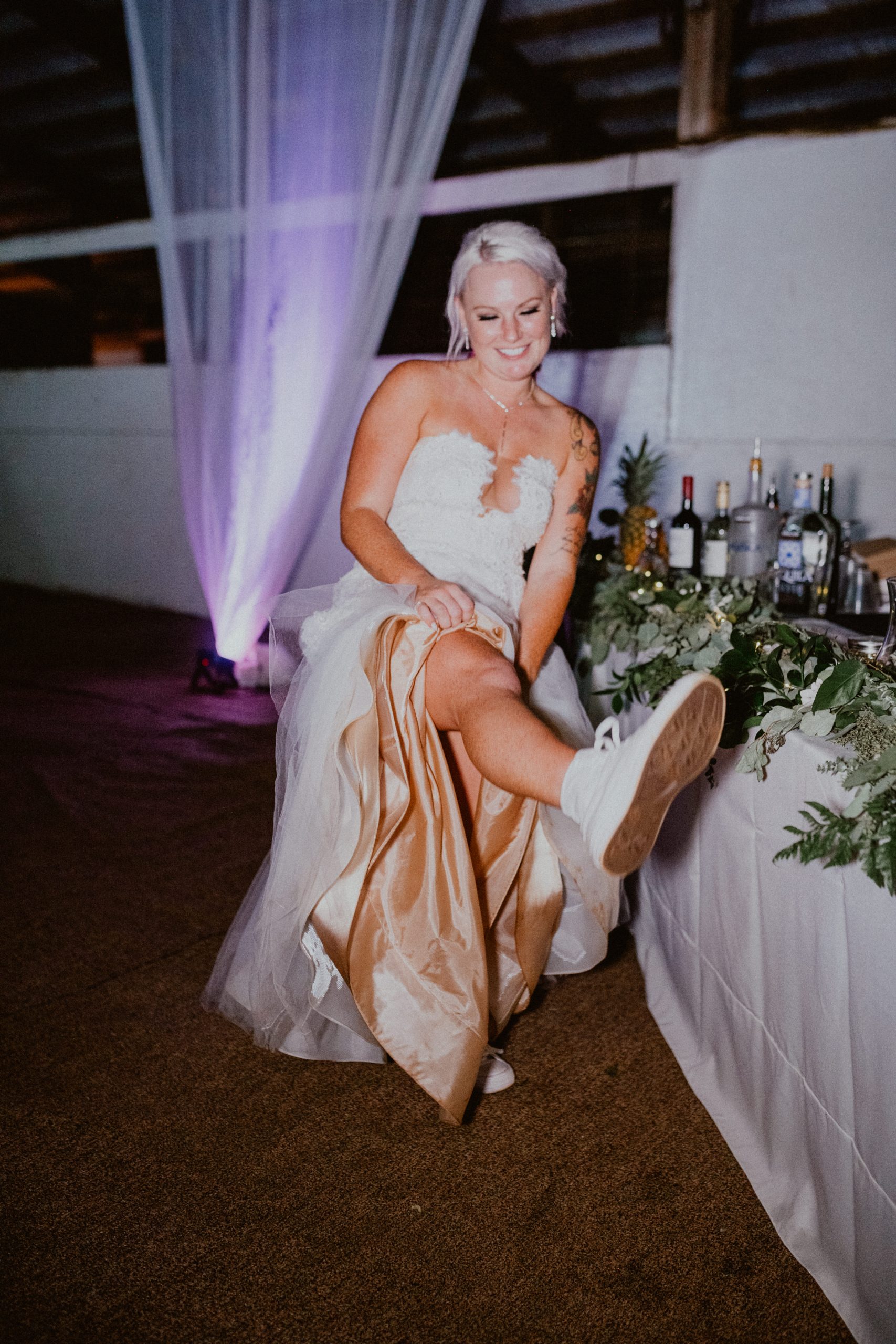 Bride shows off comfy wedding day converse sneakers in front of the bar while wearing her mermaid style wedding dress | Oahu Wedding Photographer, Oahu Elopement Photographer, Destination Wedding Photographer, Destination Elopement Photographer, Newlywed moments ideas, Newlywed Photography inspiration, Hawaii Elopement ideas | chelseaabril.com
