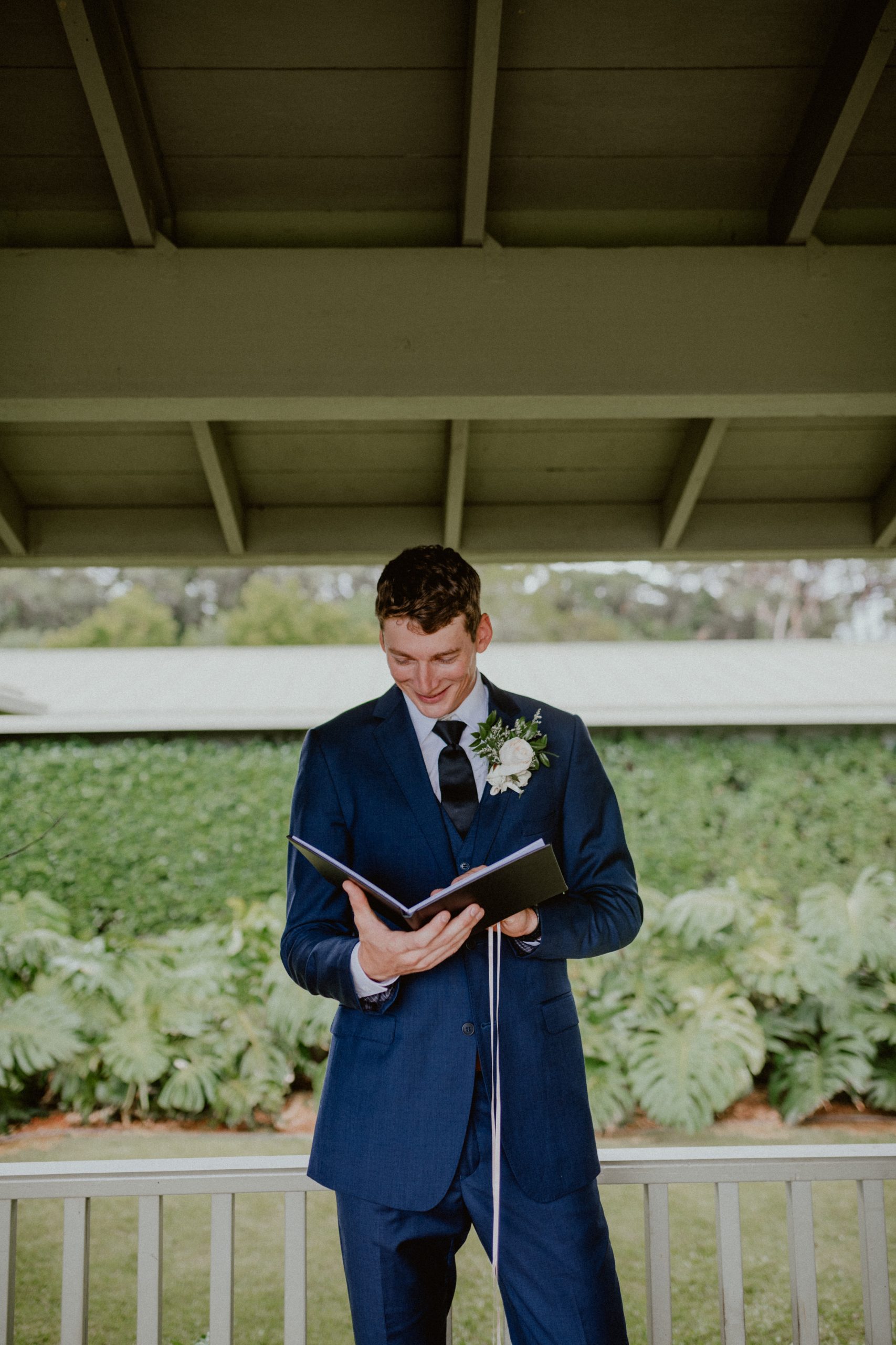 Groom reads wedding day note from bride out of a black journal while wearing white floral boutonniere | Oahu Wedding Photographer, Oahu Elopement Photographer, Destination Wedding Photographer, Destination Elopement Photographer, Newlywed moments ideas, Newlywed Photography inspiration, Hawaii Elopement ideas | chelseaabril.com