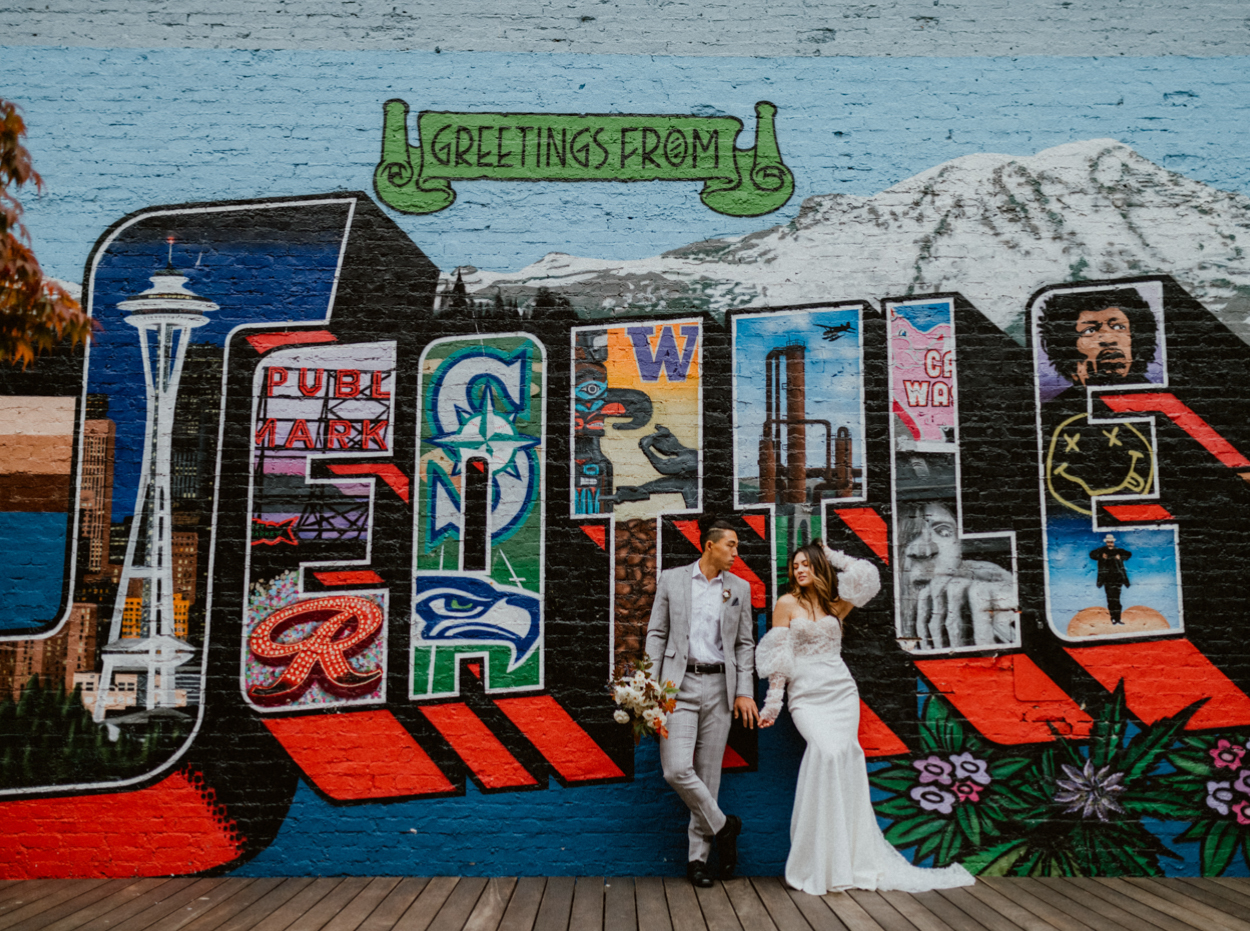 Bride and groom leaning against a wall with graffiti