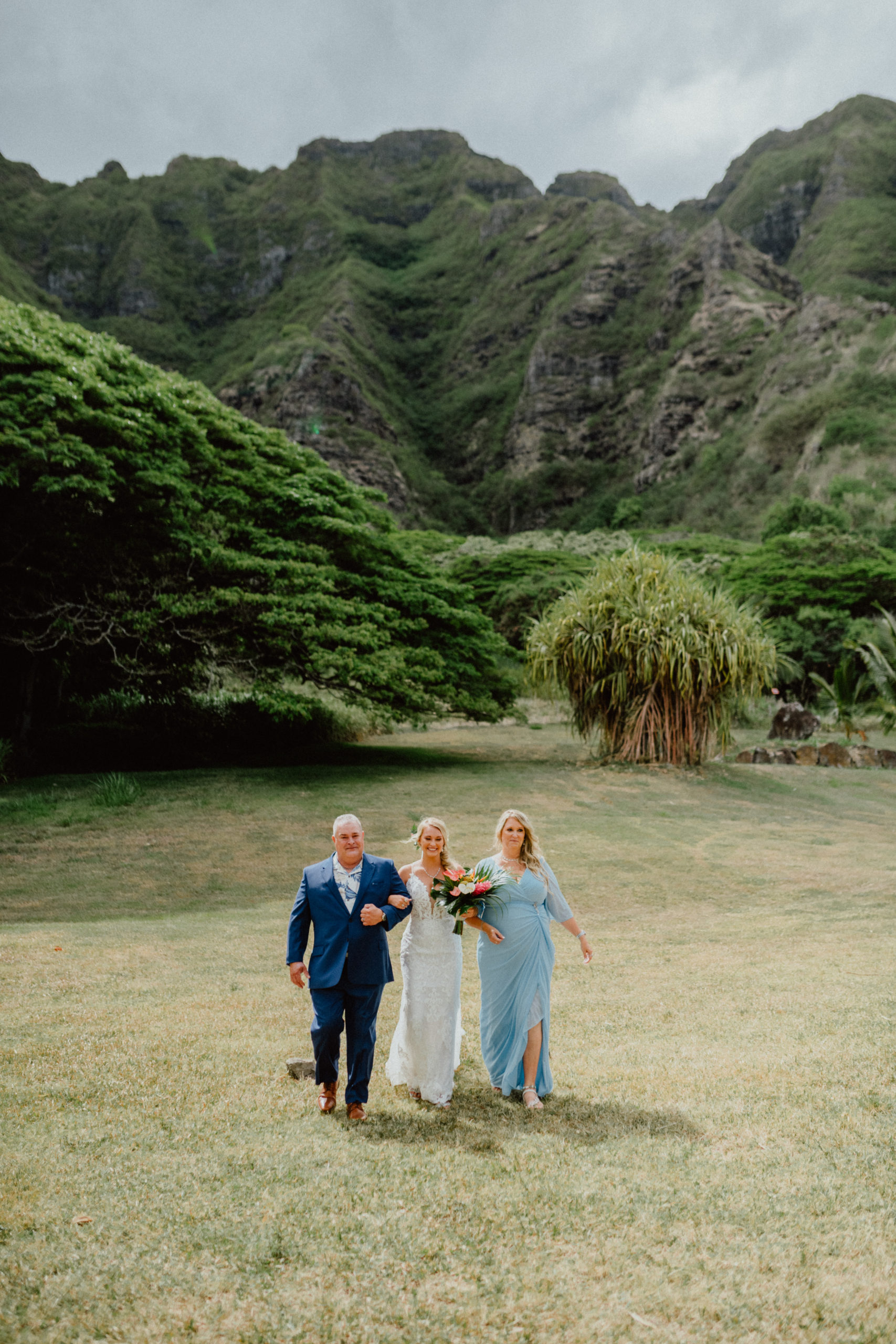 Bride escorted by mom and dad to her wedding in Paliku Gardens Venue at Kualoa Ranch