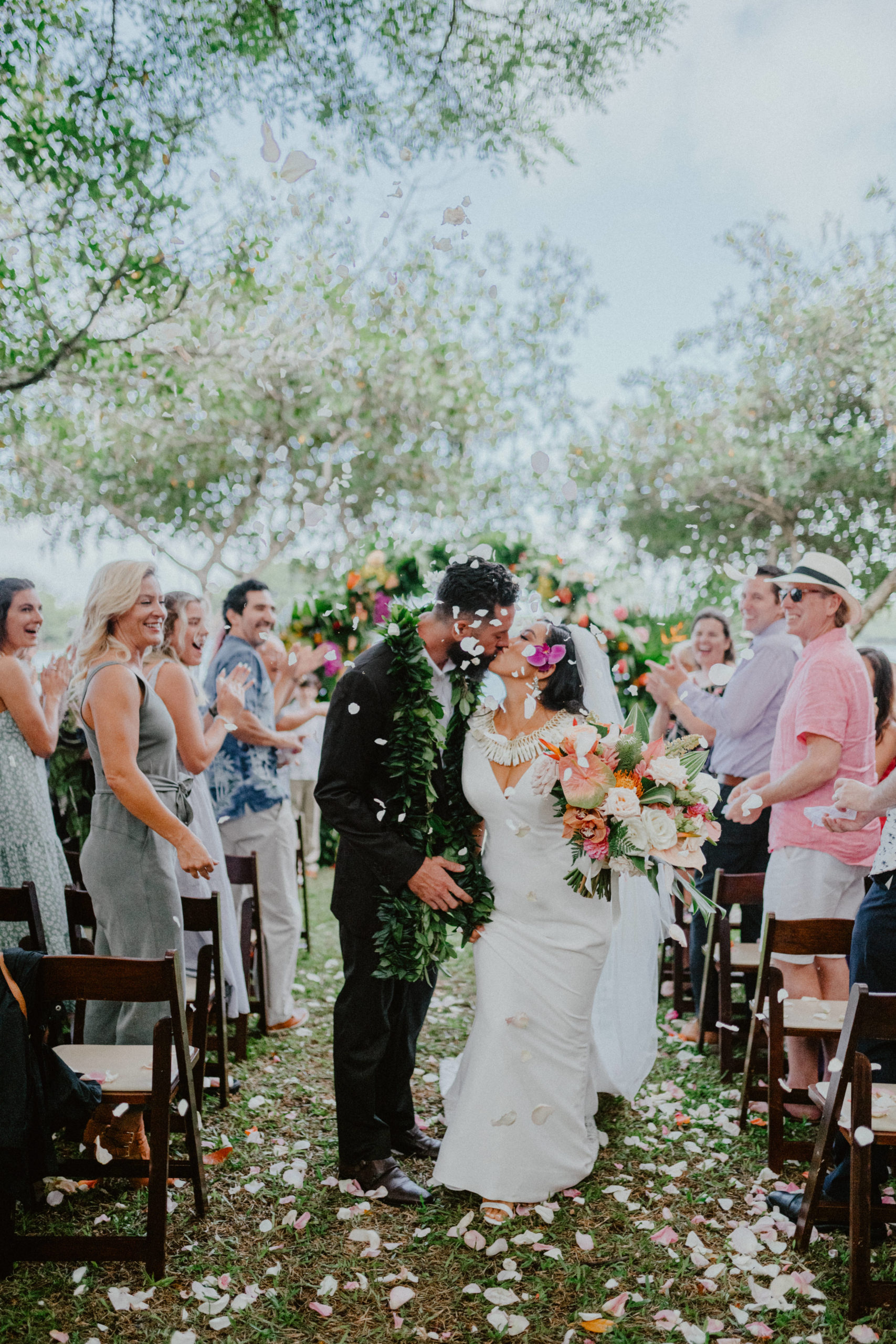 Moli'i fishpond Hawaii wedding couple kissing while showered with flower petals