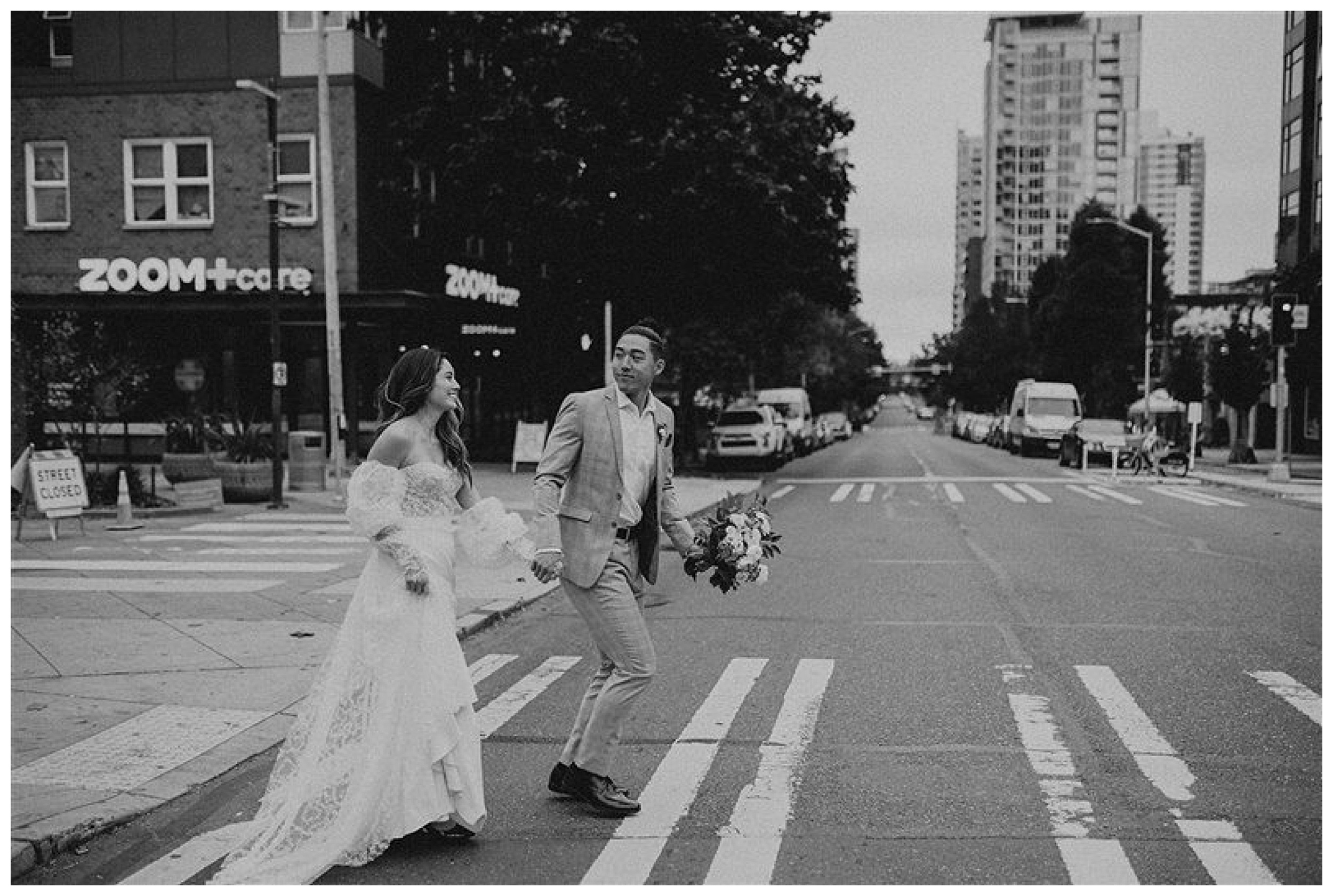bride and groom walking together across crosswalk downtown seattle 

