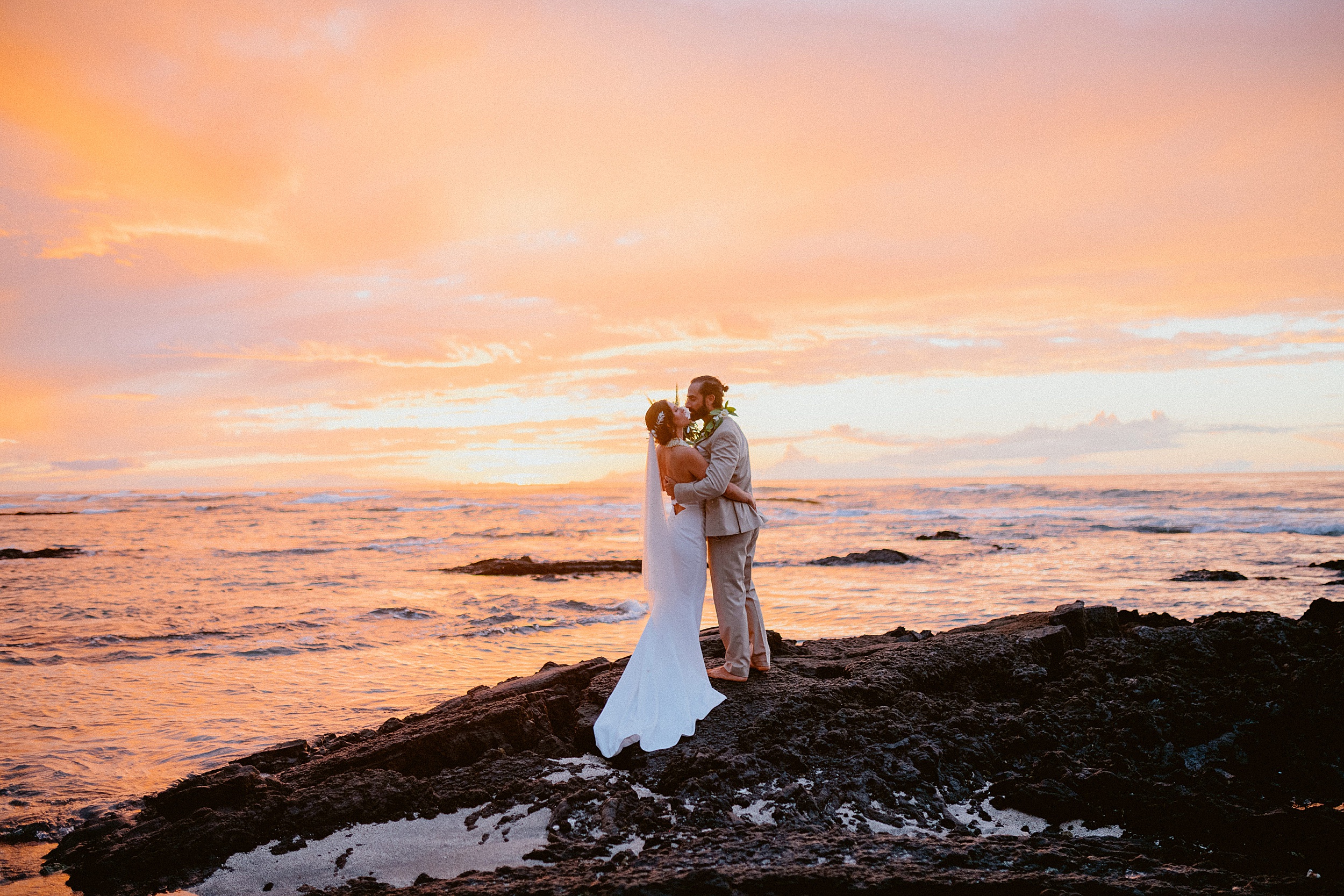 bride and groom standing together near ocean puako hawaii landscape
